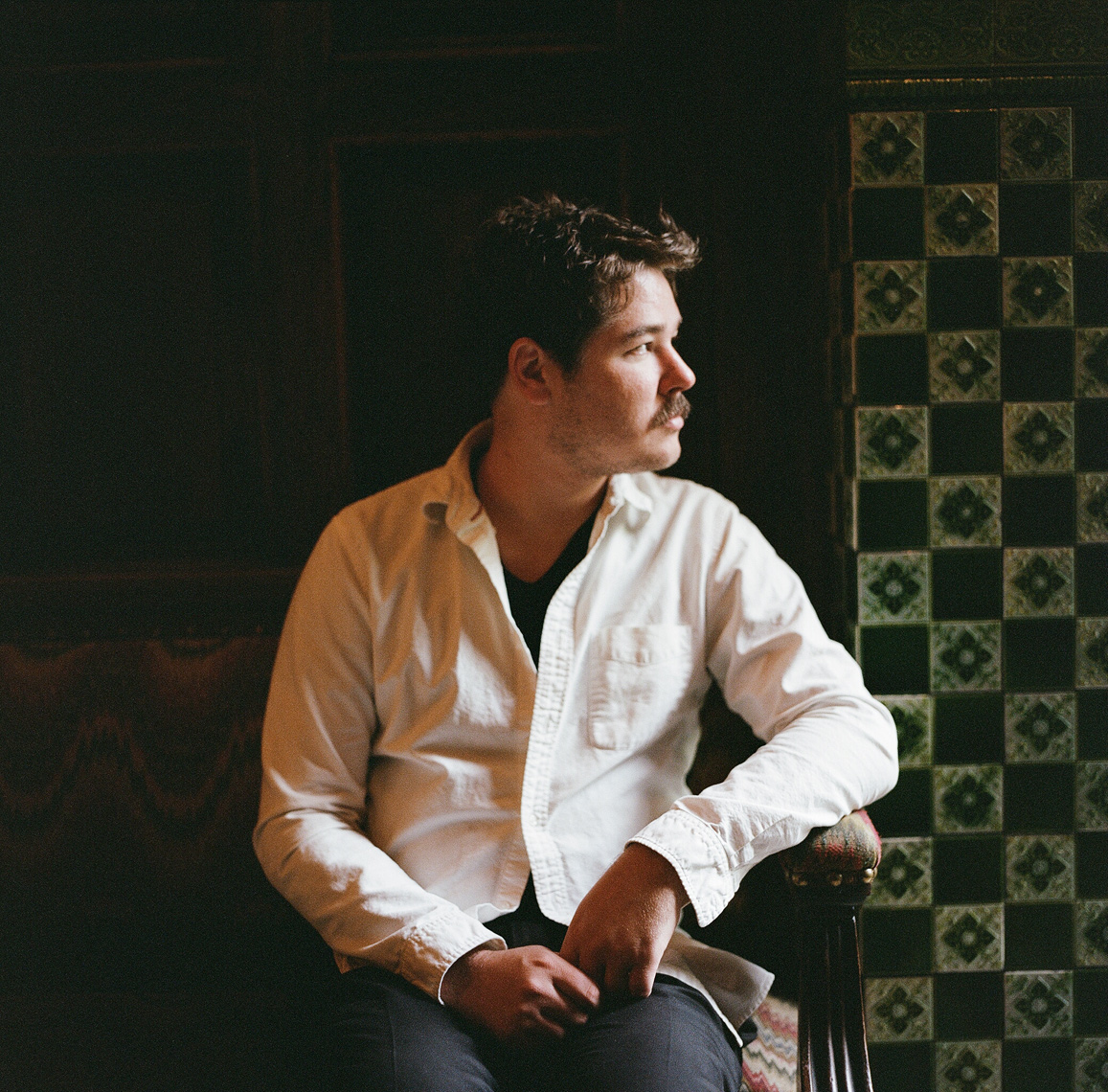 man white shirt seated moody natural light tiled wall film portrait photography