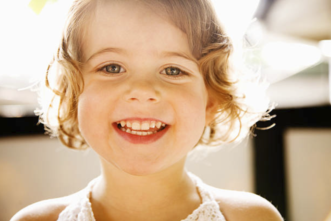 young girl smiling curly hair golden light portrait