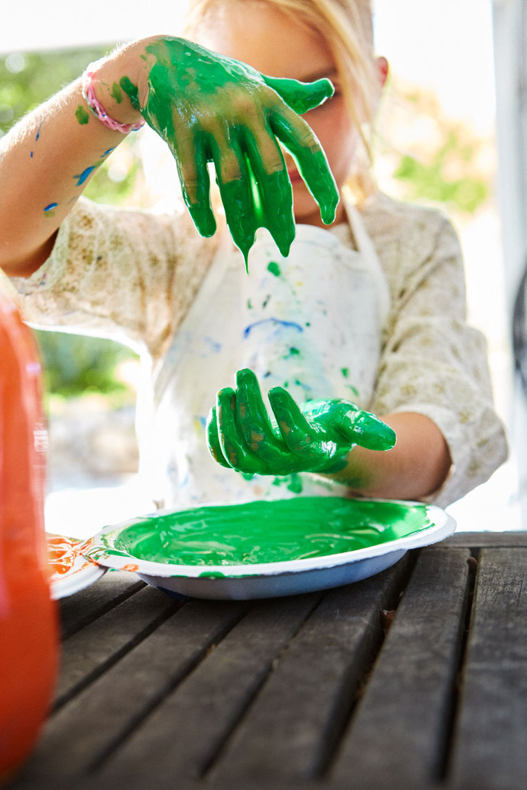Child with green painted hands at outdoor table, Amazon Kids lifestyle editorial photography