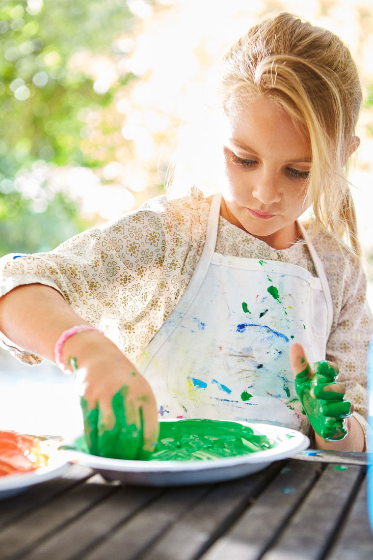 Child in apron finger painting outdoors, Amazon Kids lifestyle editorial photography
