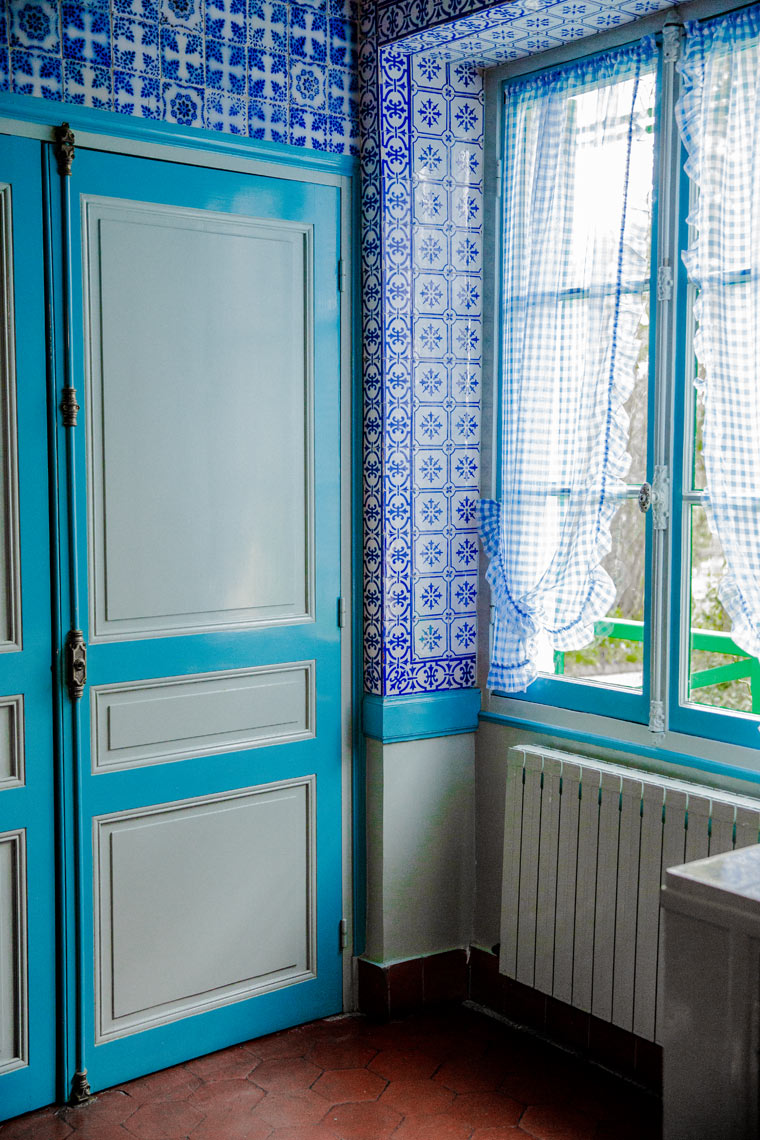Blue French doors with lace curtain against blue tile wall, travel interior editorial photography