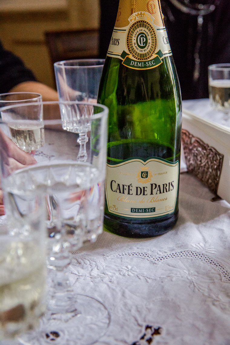 Café de Paris champagne bottle with glasses on linen table, lifestyle detail photography