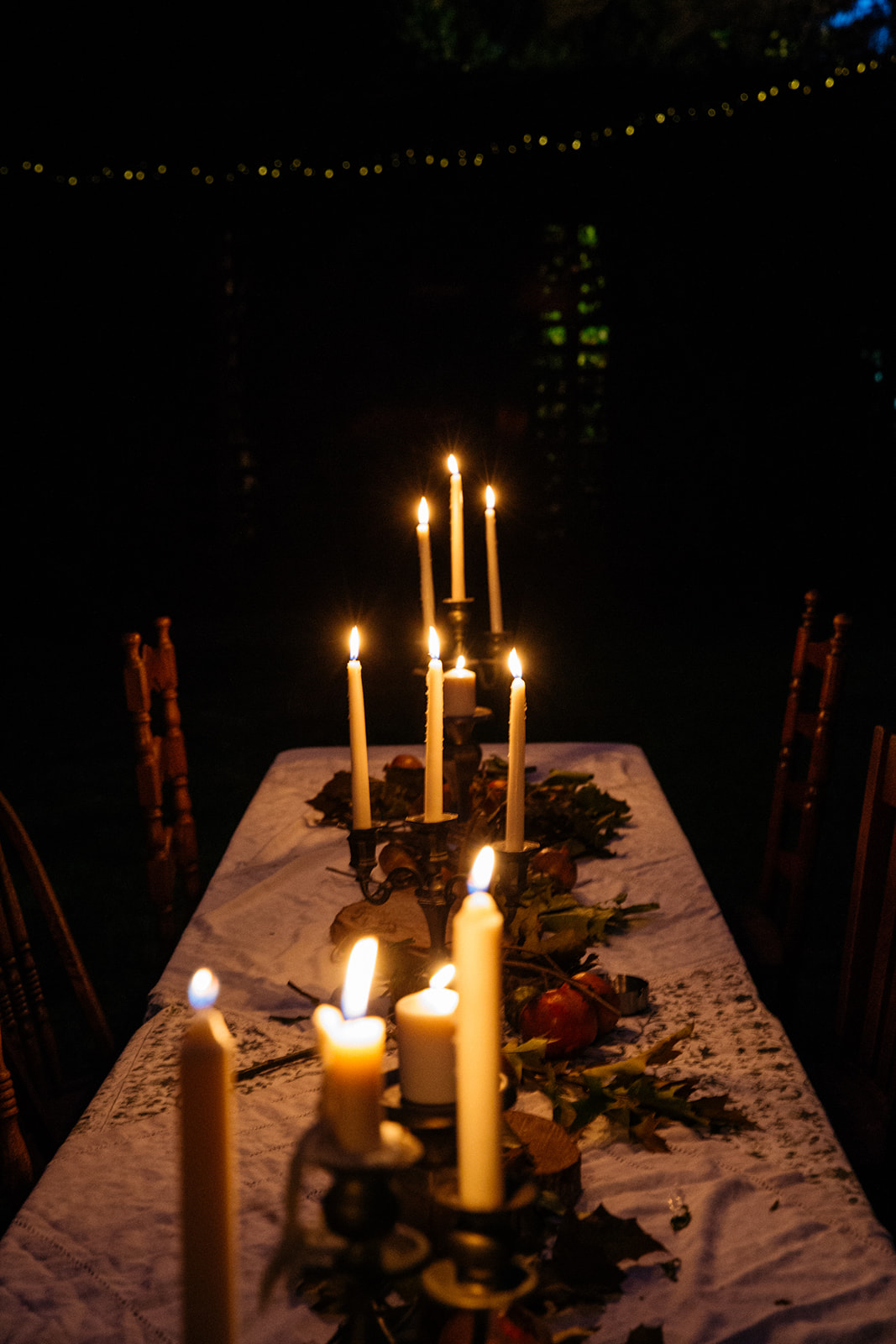 Candlelit outdoor dinner table with taper candles at night, luxury lifestyle editorial photography