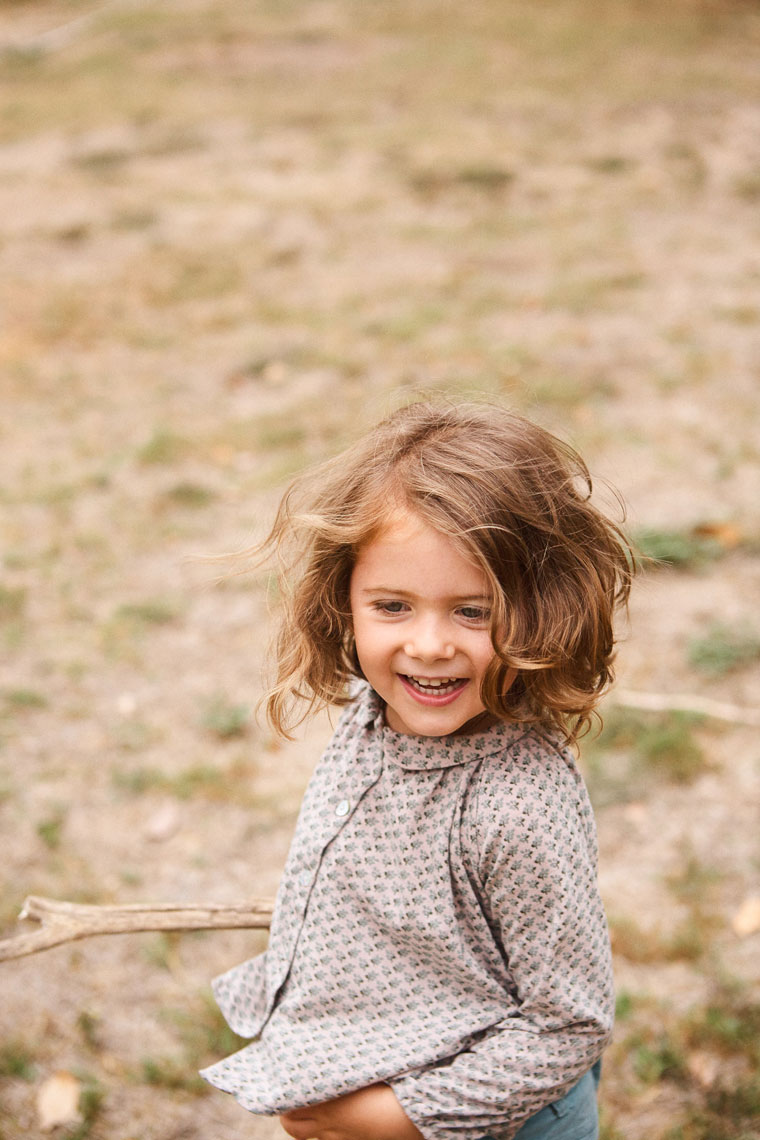 Young child laughing in golden field with natural light, lifestyle family editorial photography