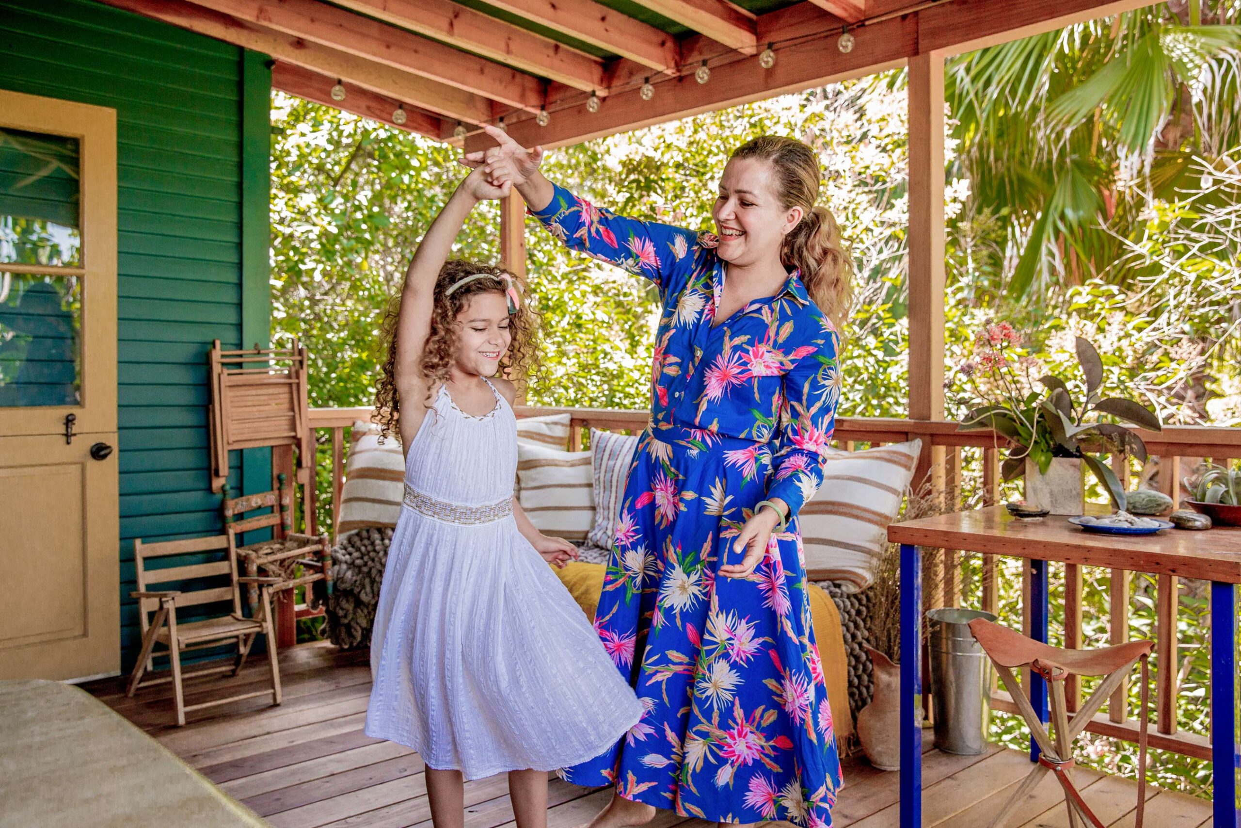 Child on porch with adult in warm golden tones, lifestyle family photography