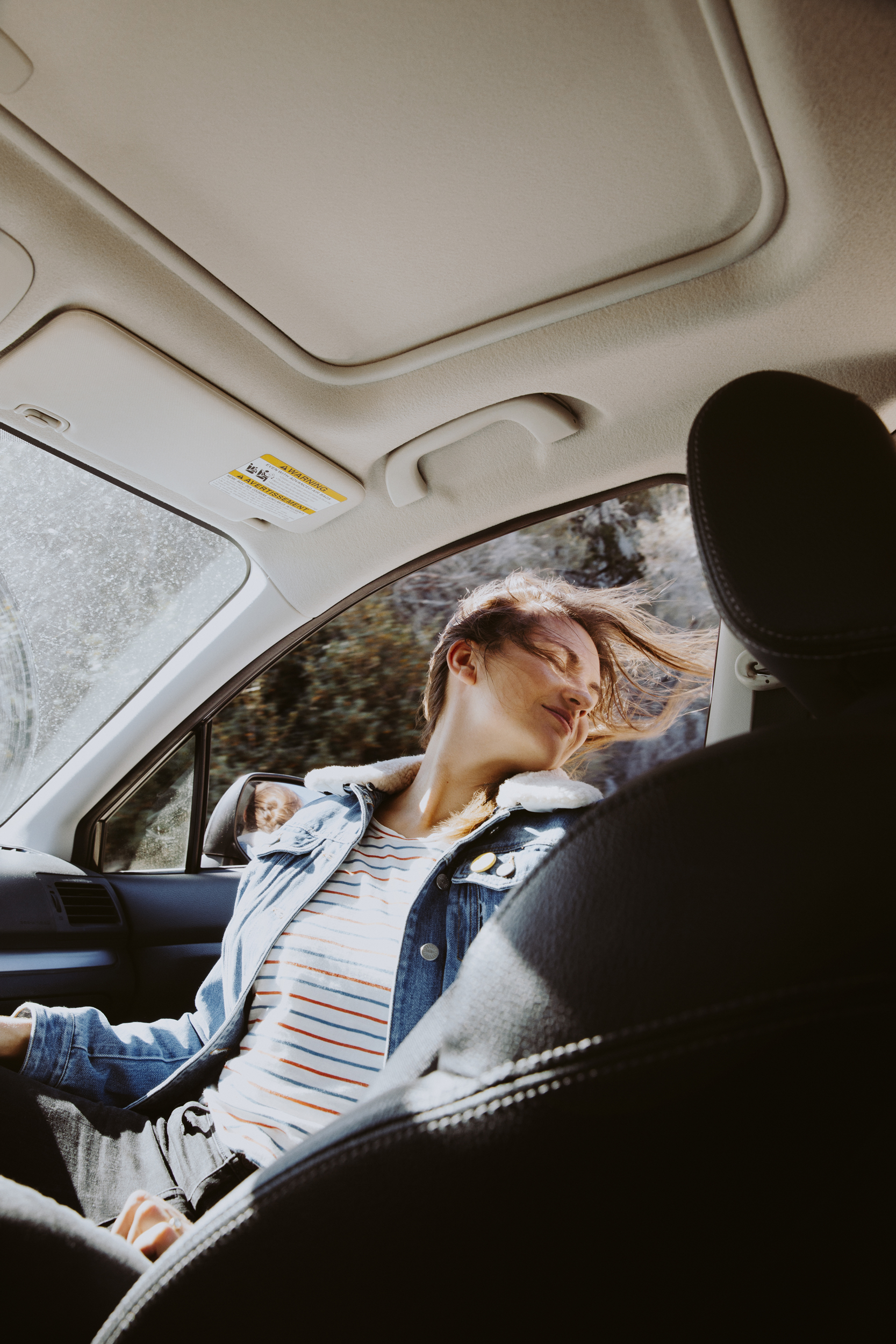 Woman with hair blowing in car interior, cinematic lifestyle editorial photography