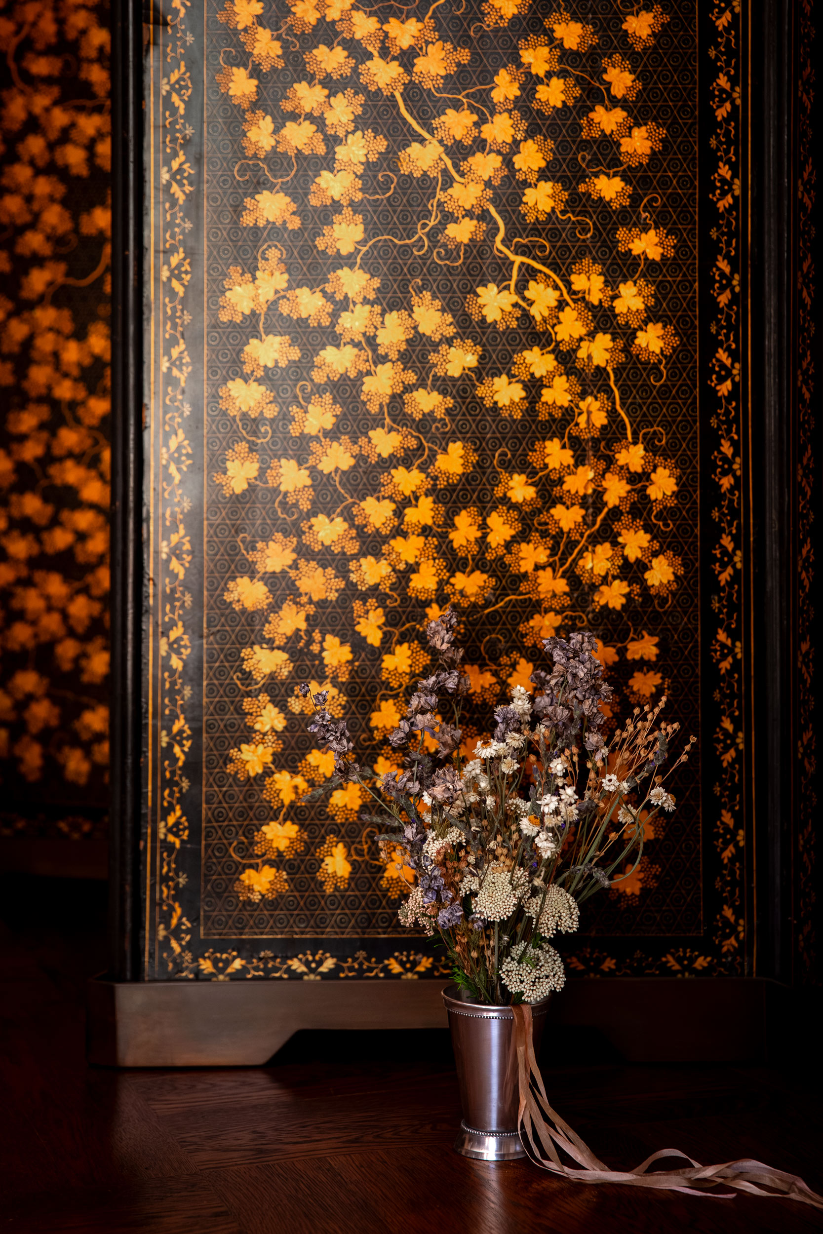 Dried botanical arrangement against rich gold wallpaper, luxury interior editorial photography