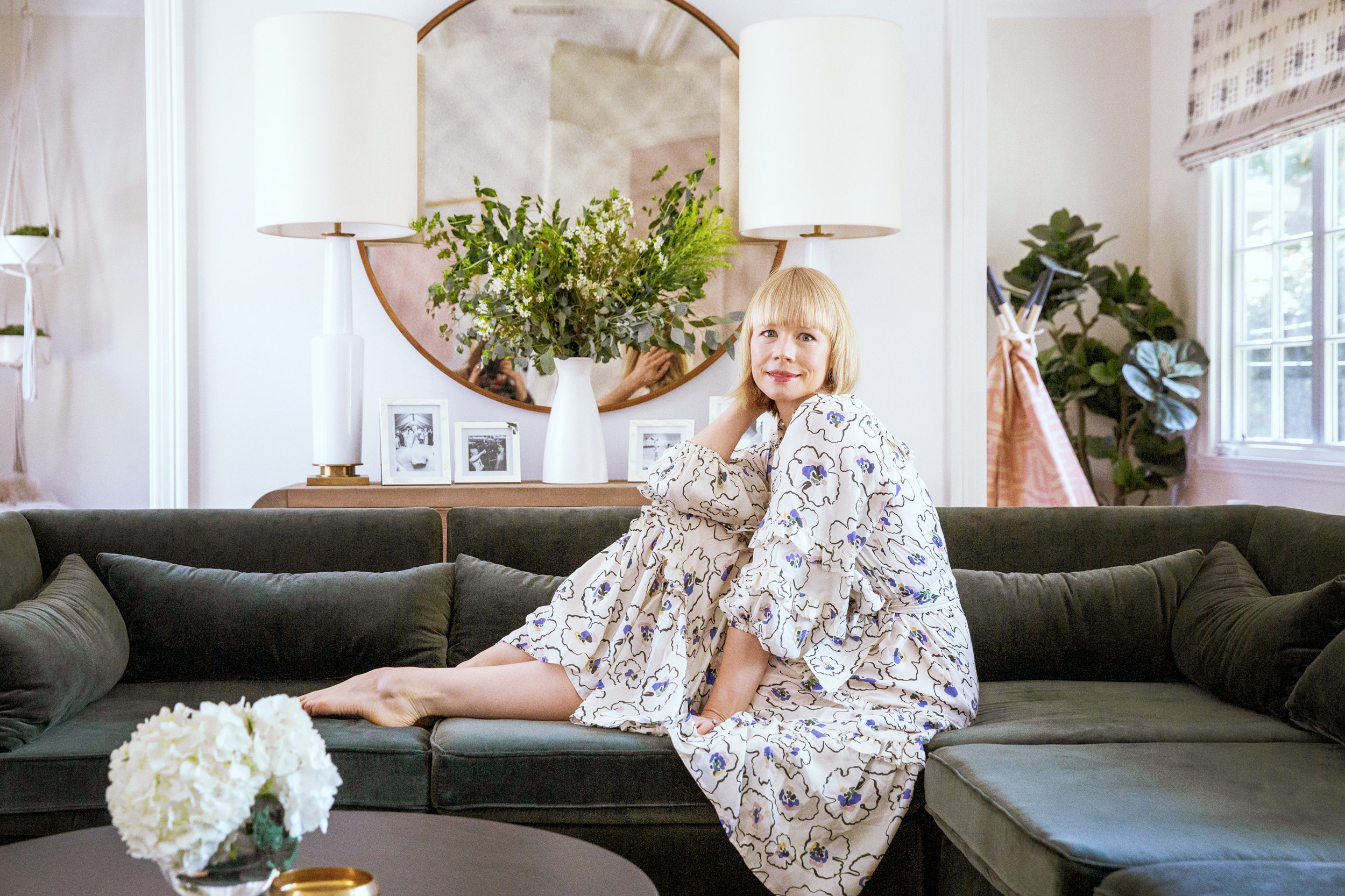 Young girl relaxing on dark velvet sofa with white hydrangeas, luxury interior lifestyle photography