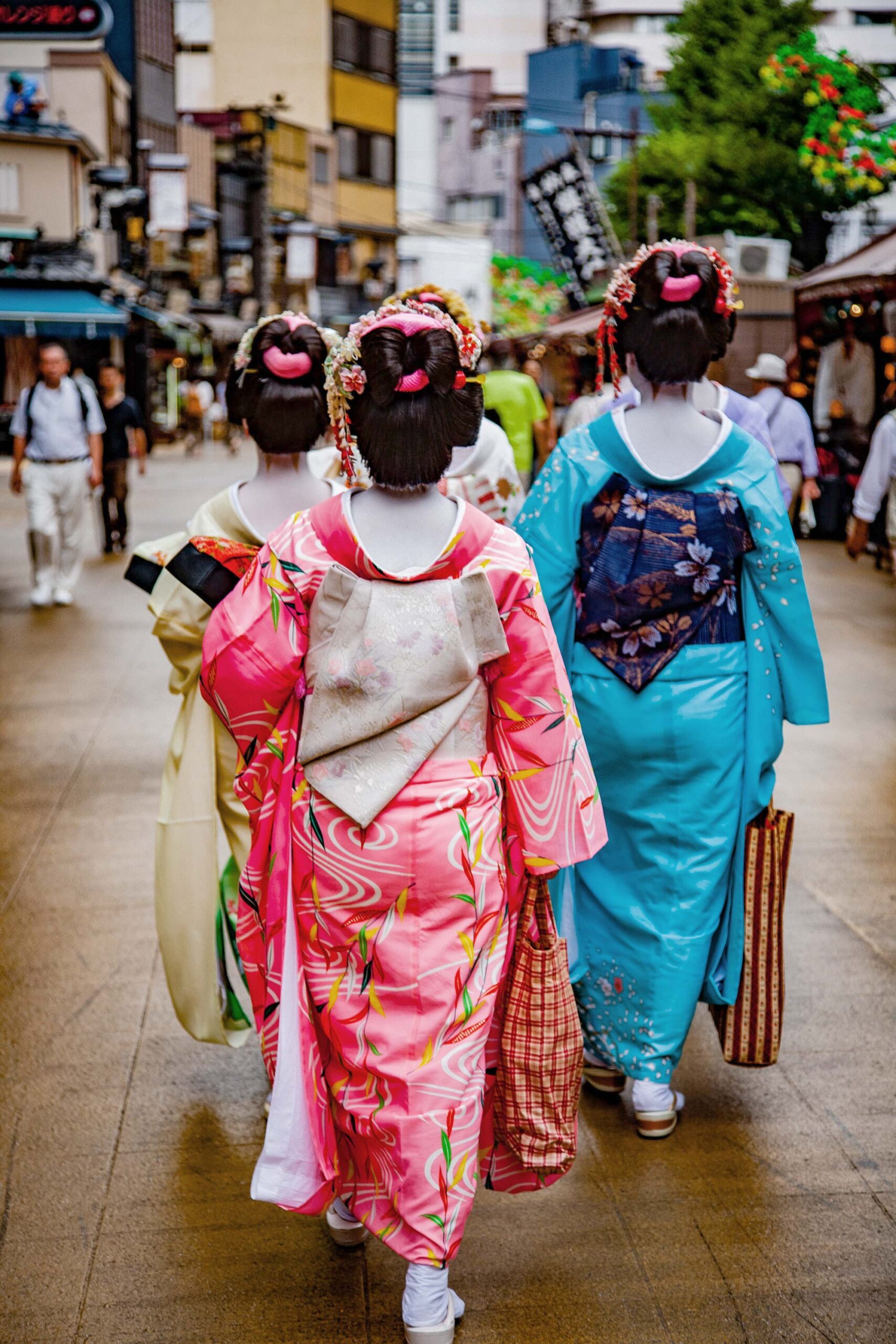 Women in traditional kimono walking through Kyoto street market, travel editorial photography