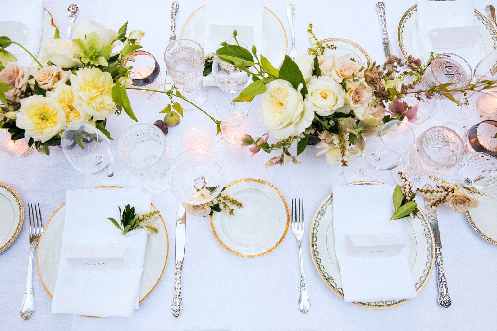 Luxury wedding tablescape with gold rim plates and white floral centerpiece, overhead detail