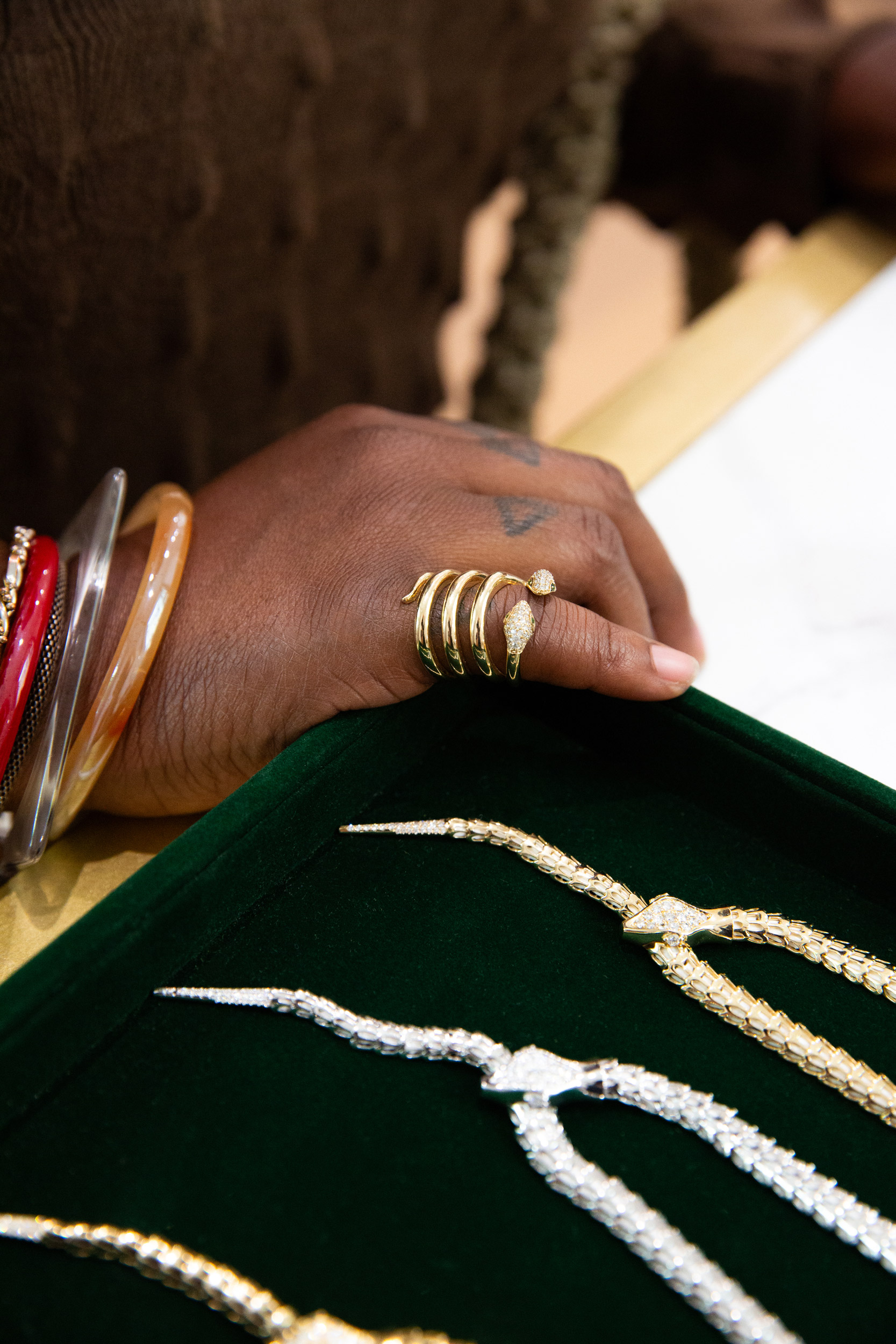 Miraco gold coil ring hand green velvet display gold silver chain necklaces luxury jewelry brand photography