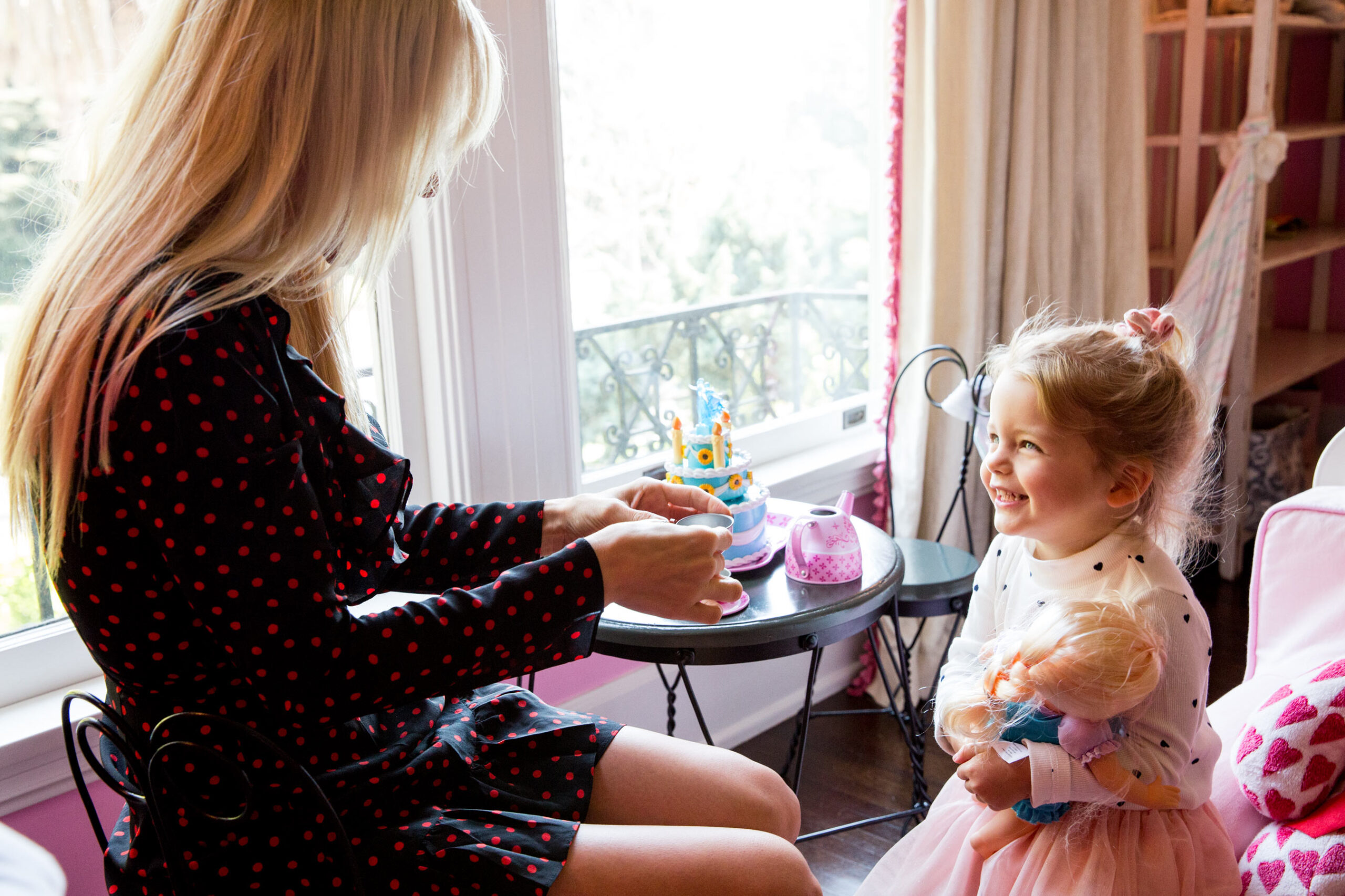 Mother and young daughter sharing tea party by window light, lifestyle editorial photography for family and children