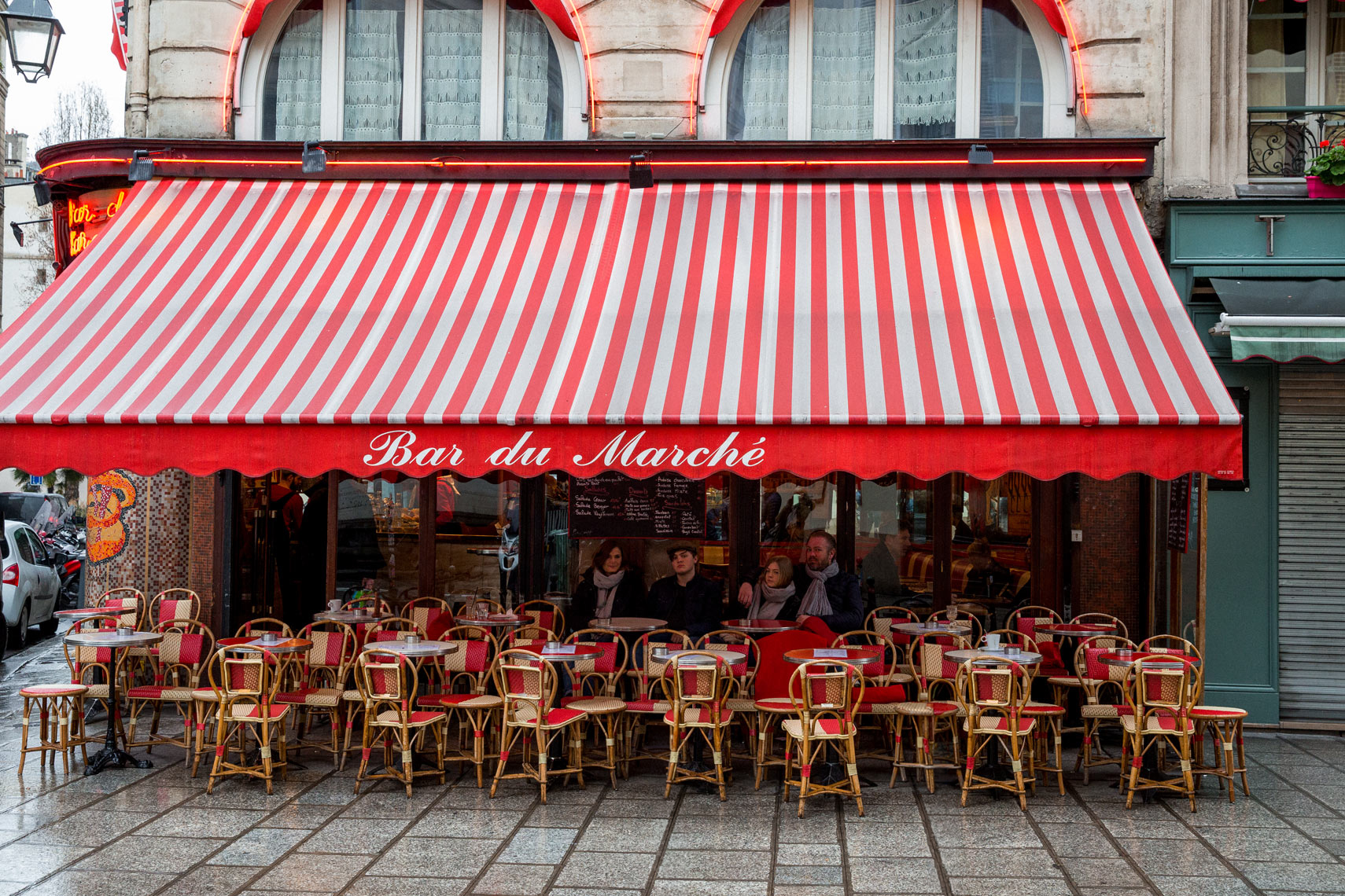 Parisian café with red striped awning and street chairs, travel editorial lifestyle photography