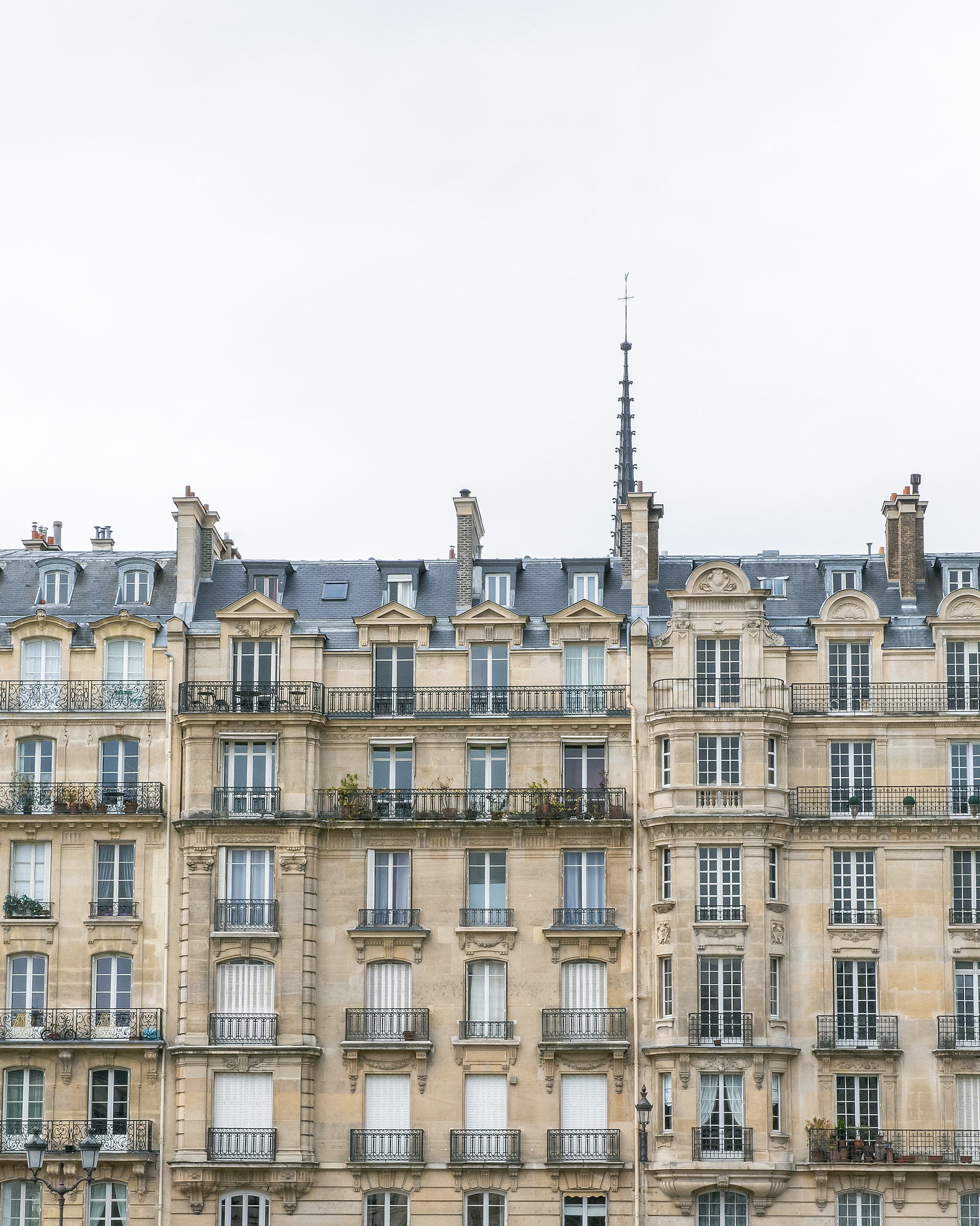 Paris Haussmann building facade iron balconies overcast sky travel editorial photography