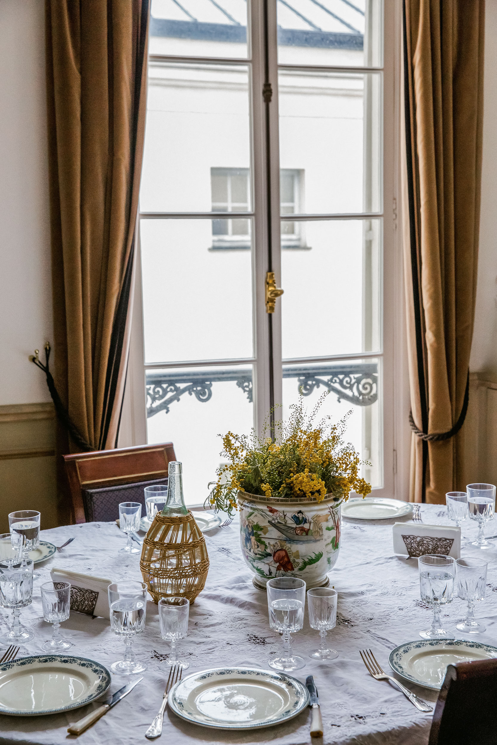 Paris private residence dining table mimosa flowers ornate vase French windows velvet curtains travel editorial photography