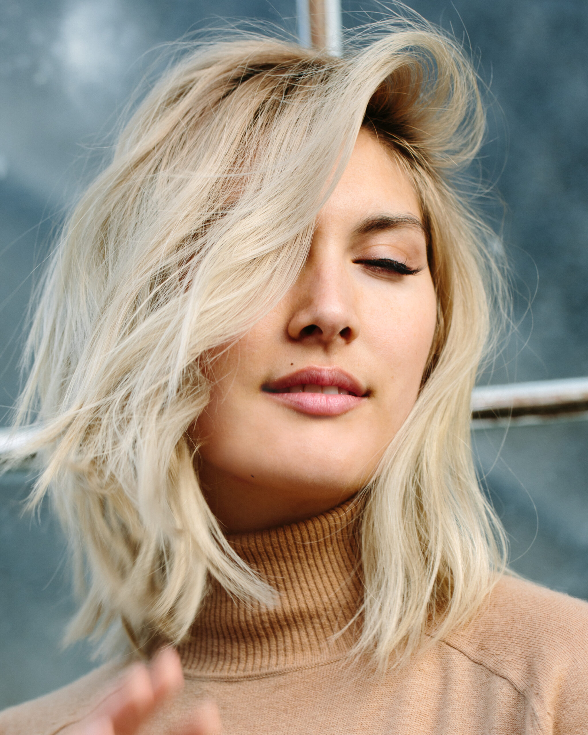 Portrait of blonde woman with natural hair movement, soft natural light, editorial beauty photography