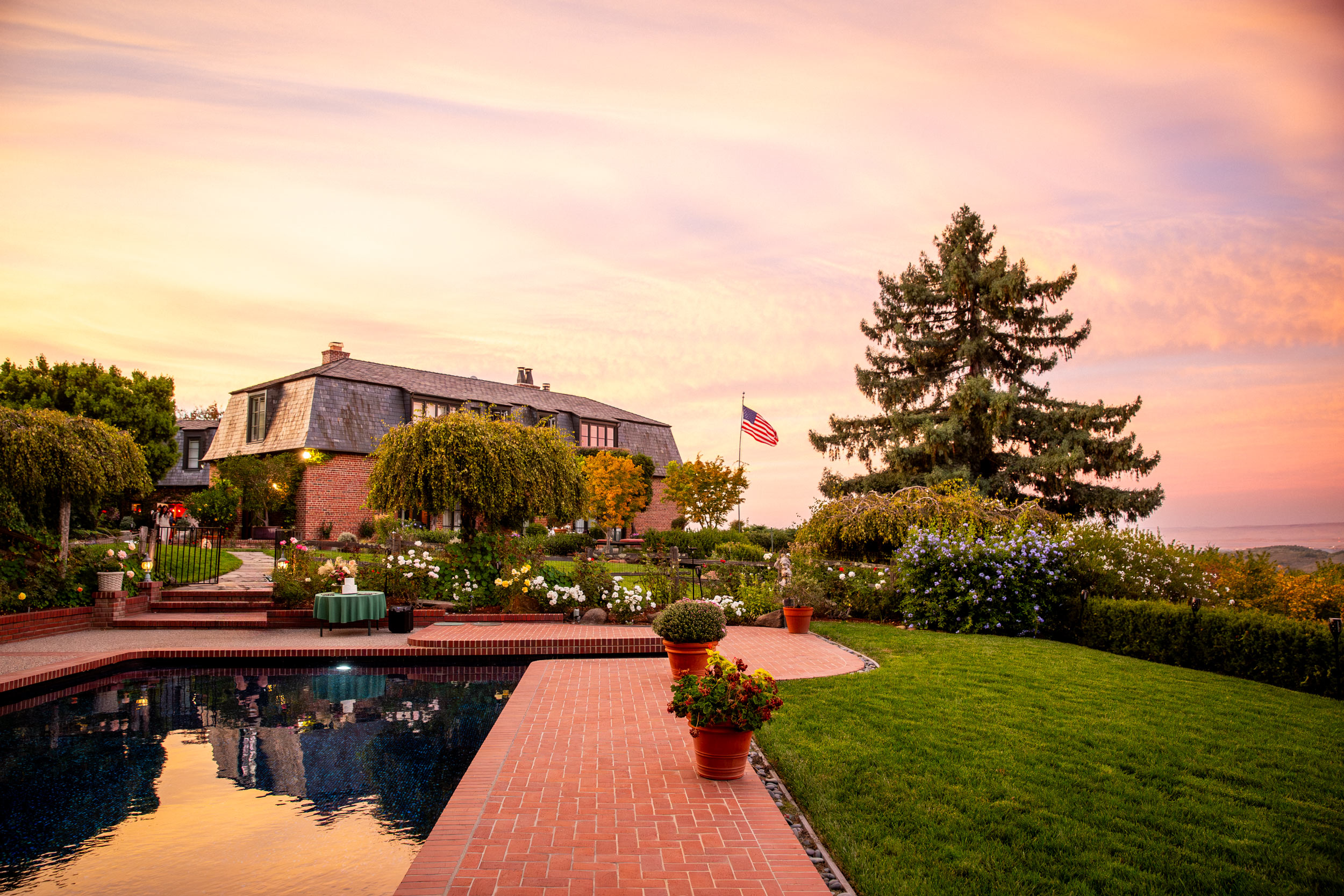 Private estate at dusk with pool reflection and pink sunset sky, luxury lifestyle editorial photography