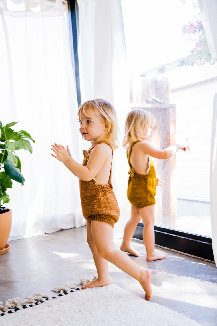 Two children running in bright white room with natural light, lifestyle editorial photography