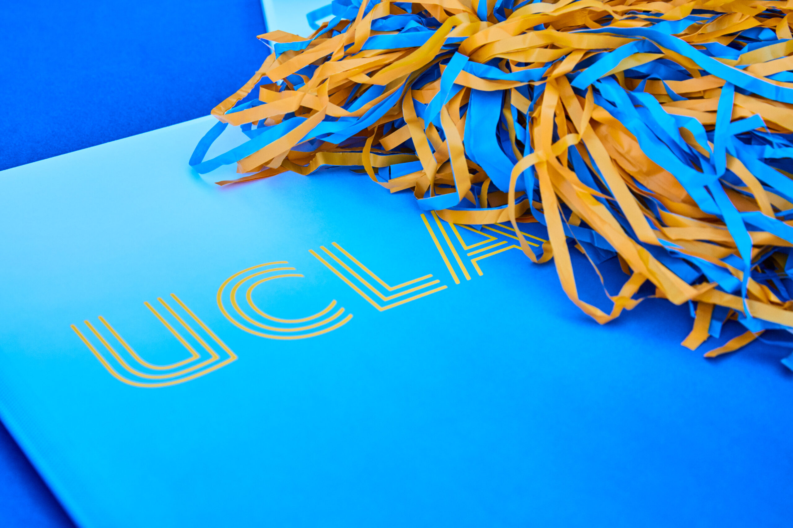 UCLA blue folder with gold lettering and blue gold pom pom, brand detail photography