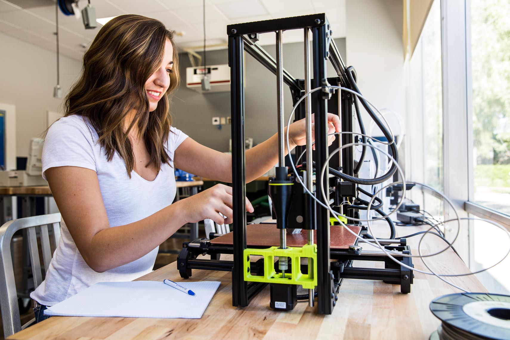 UCLA female student working on 3D printer in engineering lab, brand lifestyle photography