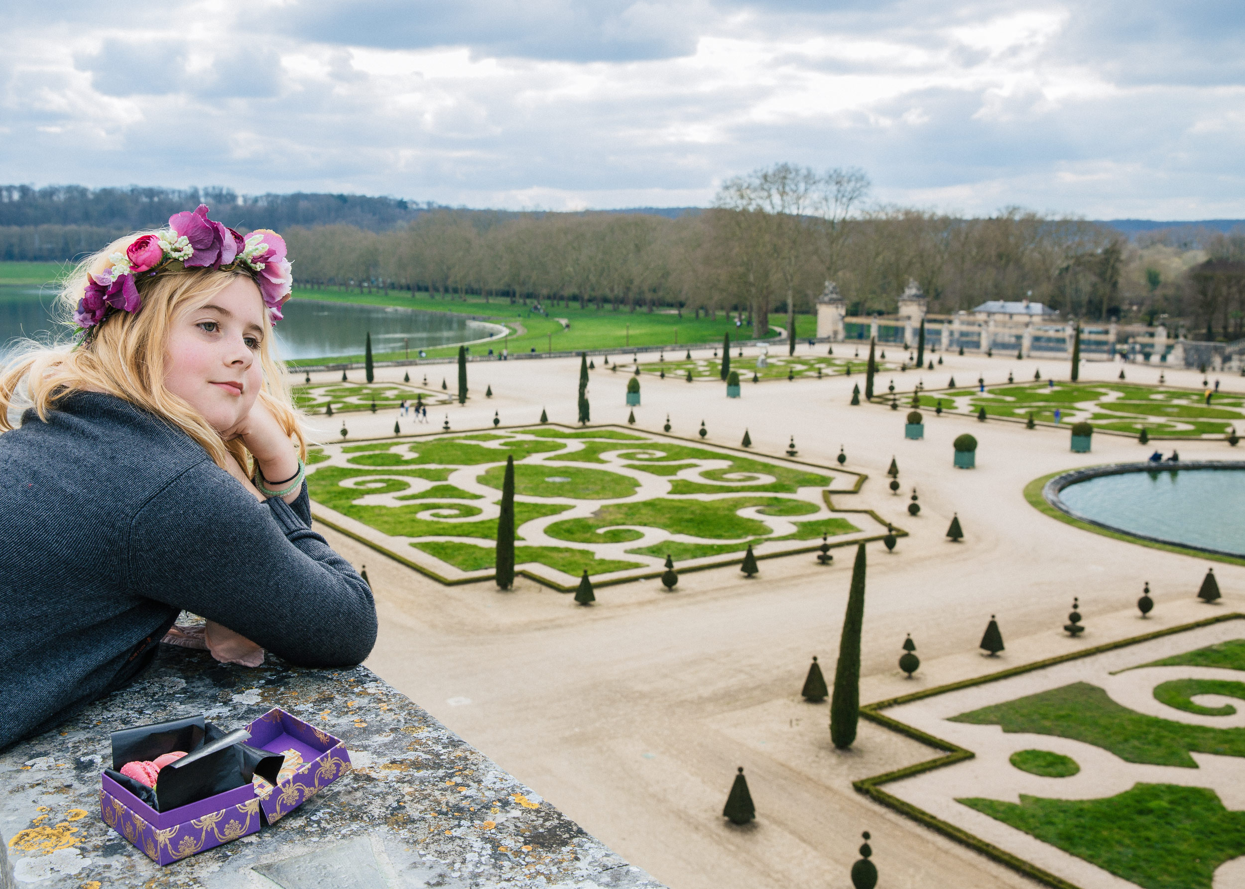 young woman flower crown sitting Versailles formal gardens Paris travel editorial photography