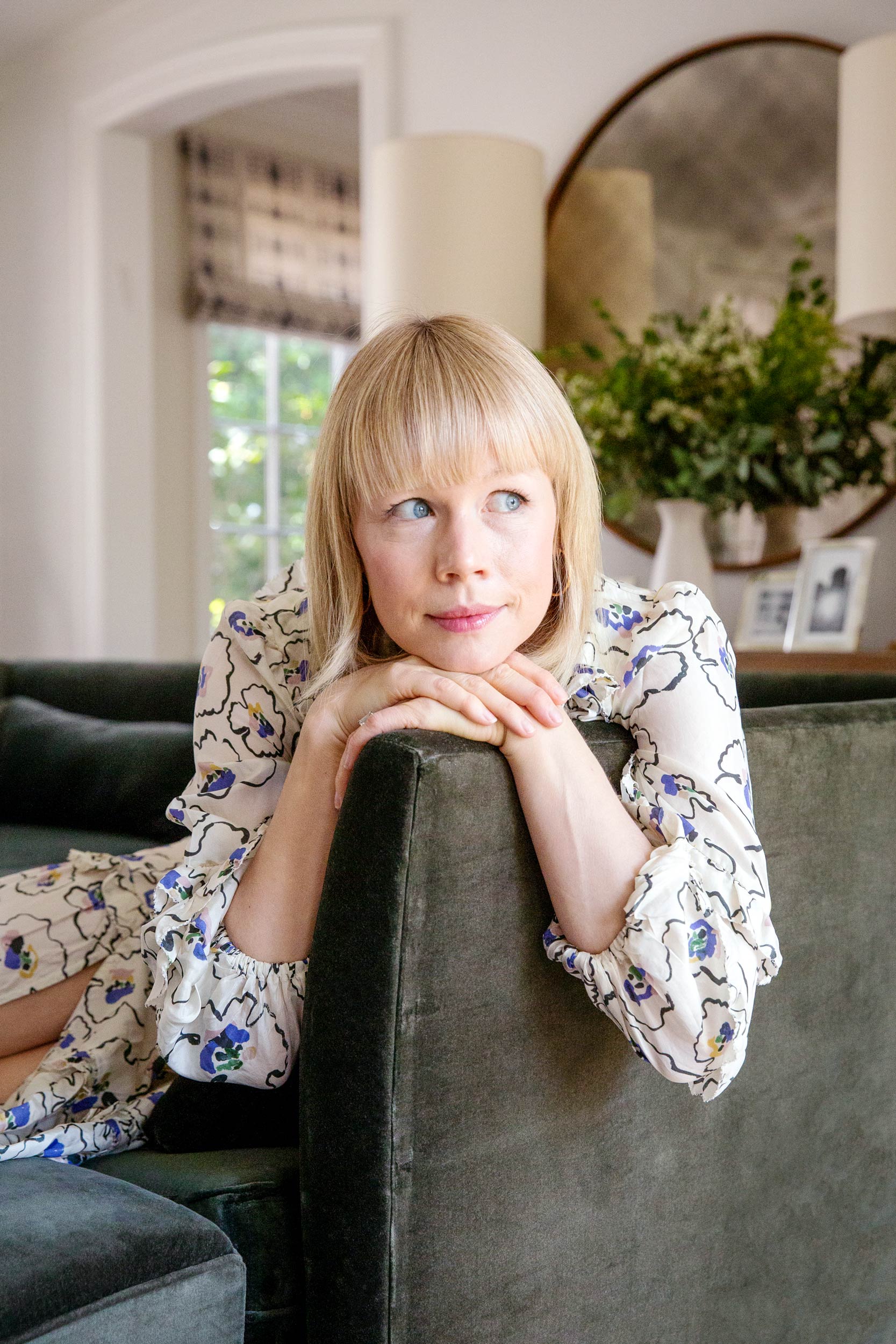 Woman leaning on velvet sofa in well-designed living space, lifestyle portrait editorial photography